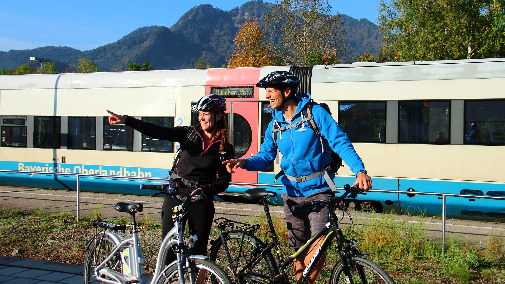 Fahrradfahrer am Lenggrieser Bahnhof mit einem Zug der Bayerischen Oberlandbahn - für sanftes Reisen in den Bayerischen Alpen, © Archiv Tölzer Land Tourismus|München-Venezia