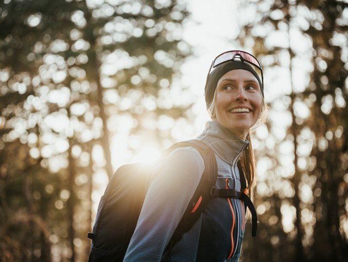 Eine sportlich gekleidete Frau lächelt glücklich während sie zum Himmel blickt, © Ooberbayern.de|Aline Köhler